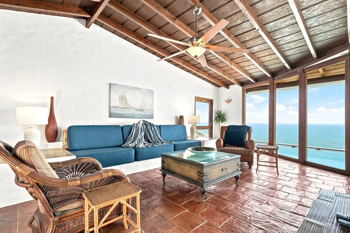 Living room with blue sofa and expansive ocean windows.