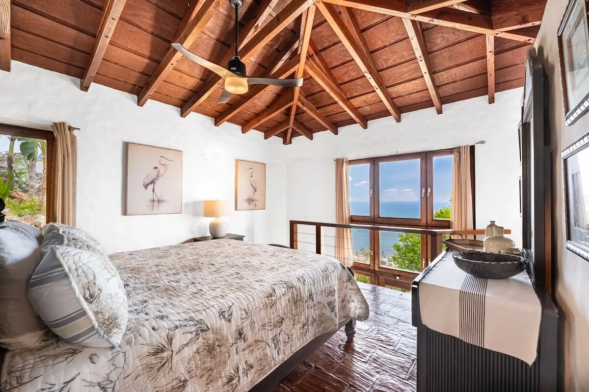 Primary bedroom with vaulted wood ceiling and ocean view.