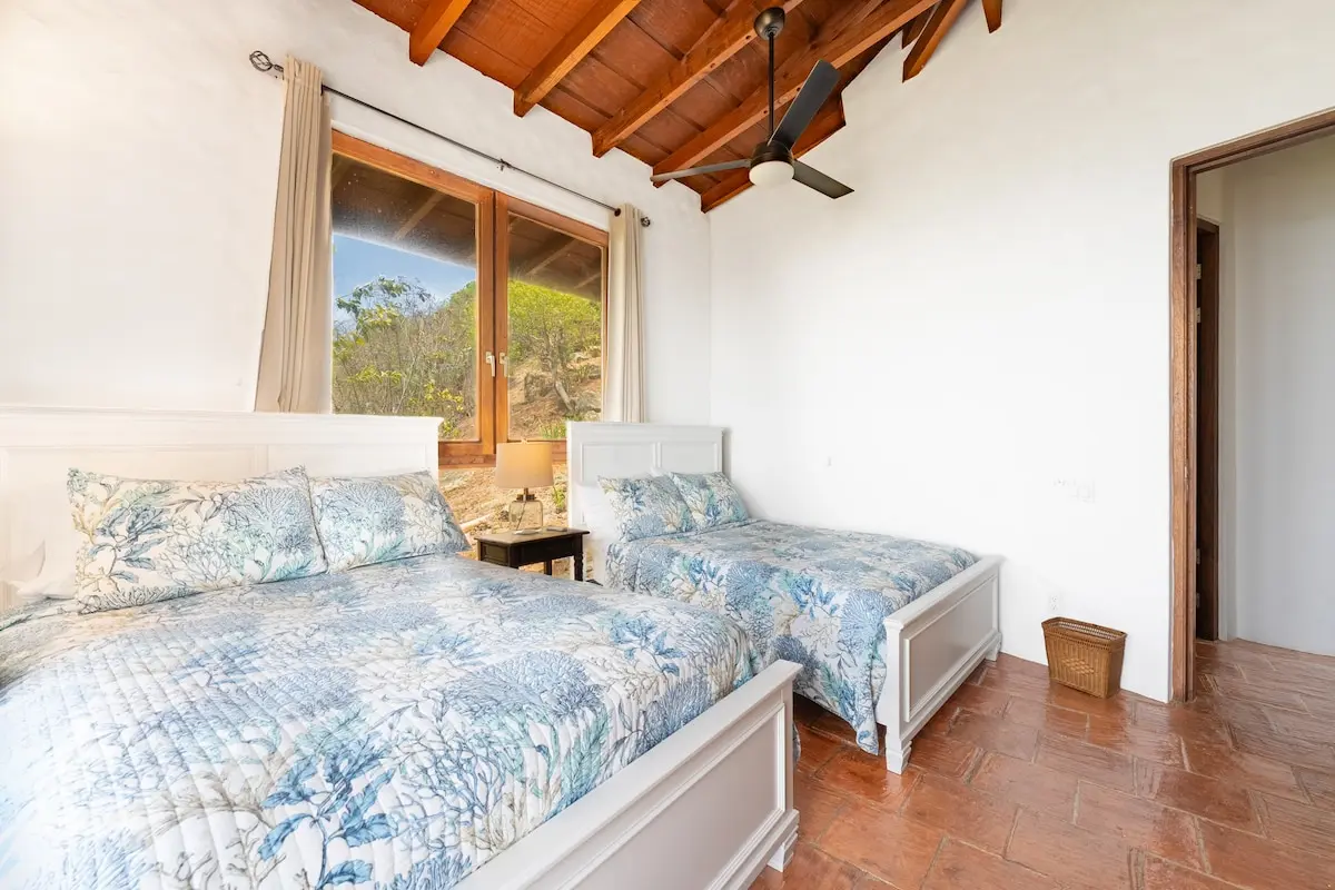 Twin bedroom with colorful linens and vaulted ceiling.