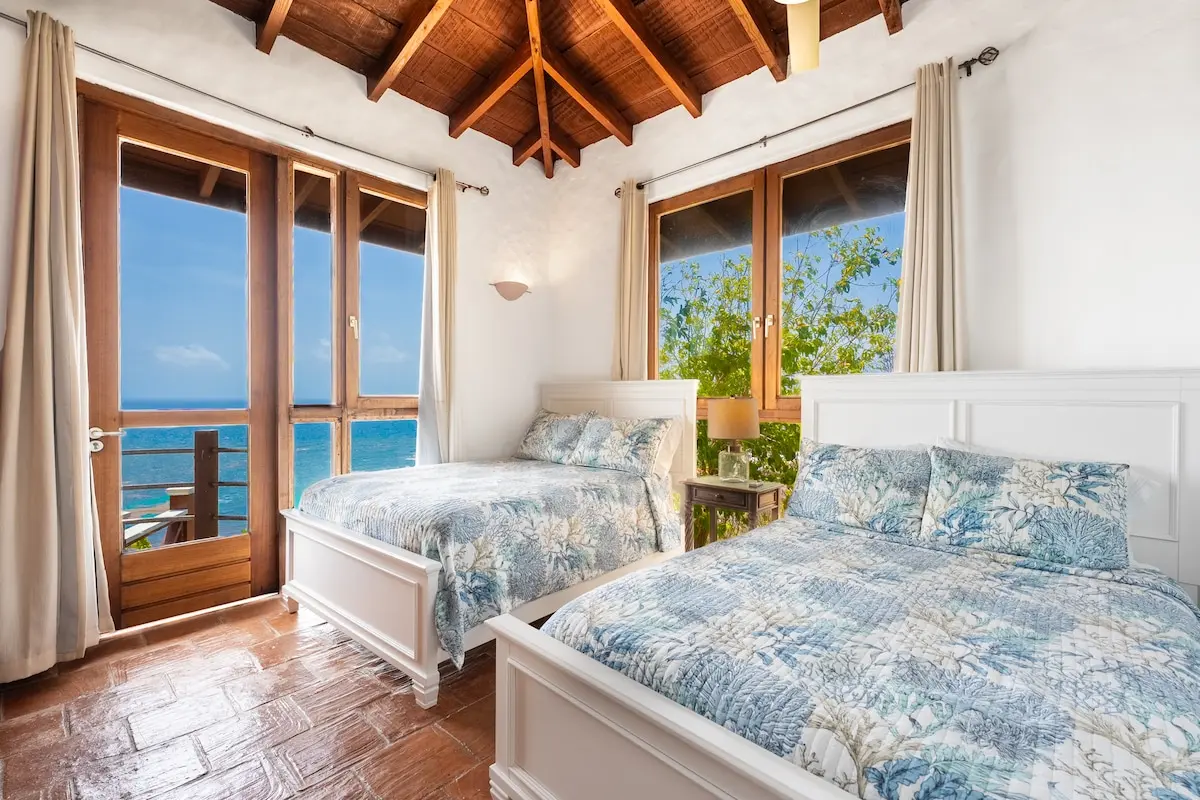 Twin bedroom with direct ocean views and balcony access.