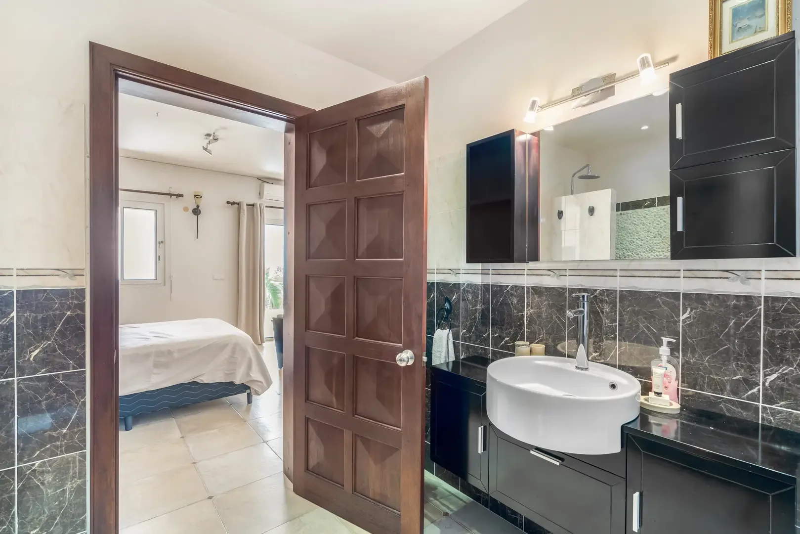 A spacious ensuite bathroom with vessel sink, chrome fixtures, and marble-effect tiles — refined comfort.