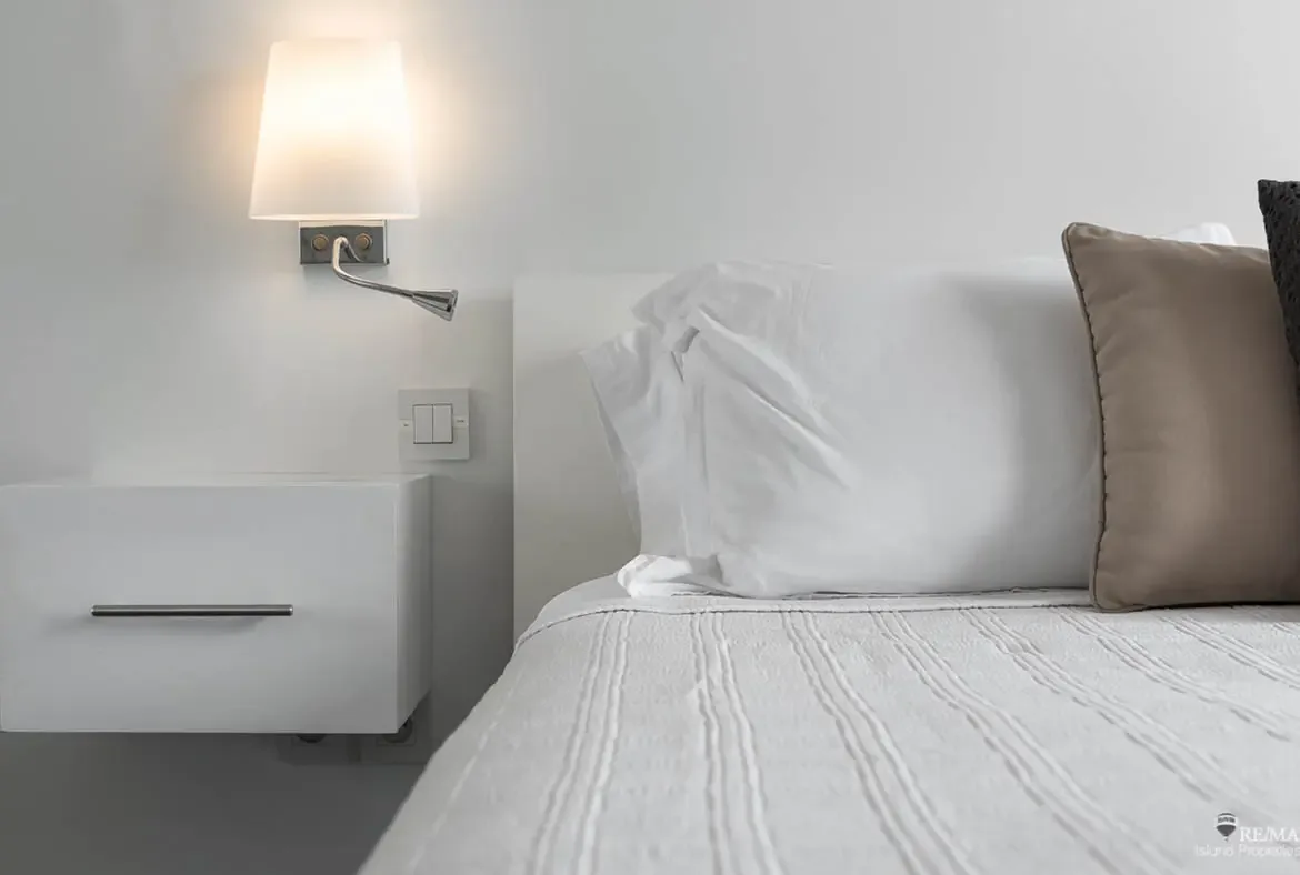 Thoughtful bedroom details include a wall-mounted reading lamp and floating nightstand — modern comfort in every corner.