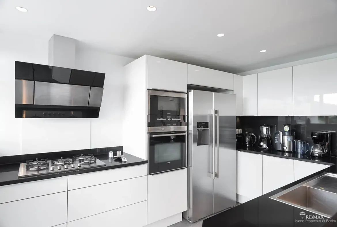 A sleek modern kitchen with black granite countertops and stainless steel appliances — cook like a chef in your Caribbean home.