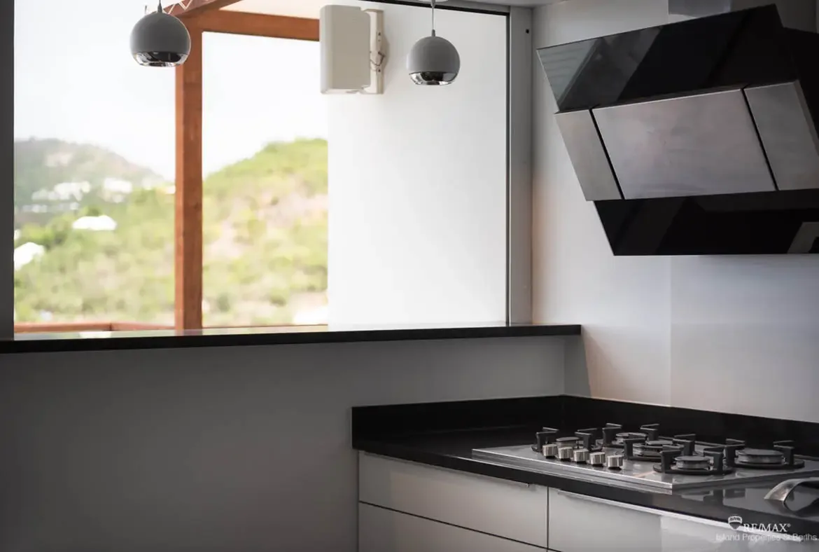 A sleek modern kitchen with center island — prepare gourmet meals with Caribbean views just beyond the windows.