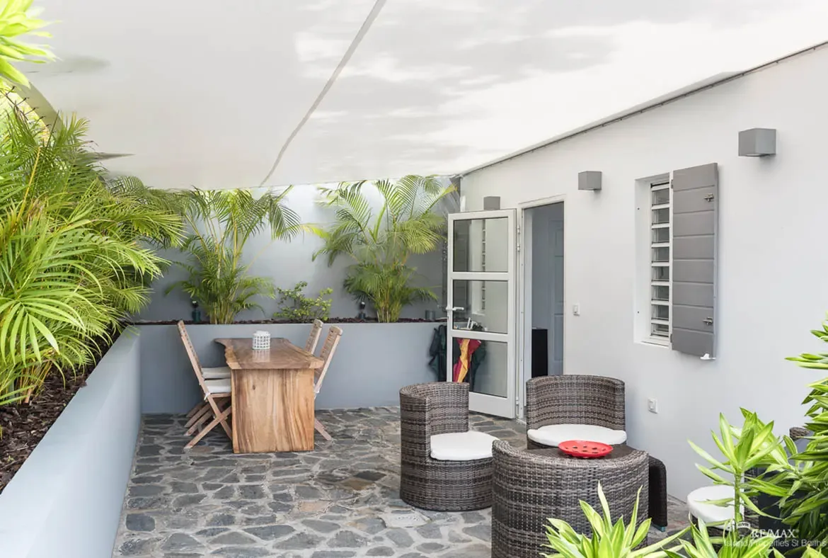A covered terrace with comfortable outdoor seating — relax in the Caribbean breeze surrounded by tropical greenery.