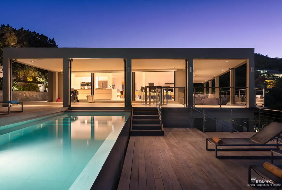 At twilight, the glowing pool and tiered wooden decks lead the eye toward Villa Arte’s sleek open-front design. With soft interior light spilling through the kitchen and lounge areas, the whole property feels calm, elevated, and ready for a long Caribbean evening.