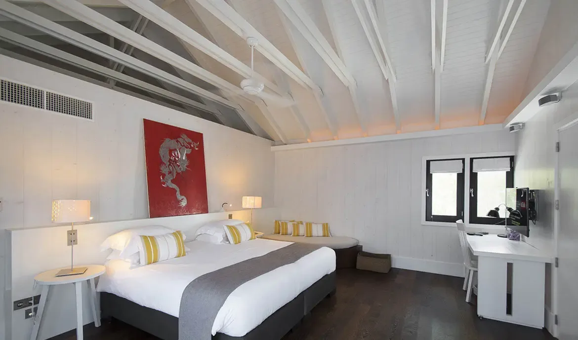 A vibrant red dragon painting anchors this minimalist bedroom with a canopy bed and yellow-striped pillows, where a built-in bench and white desk add versatile space.