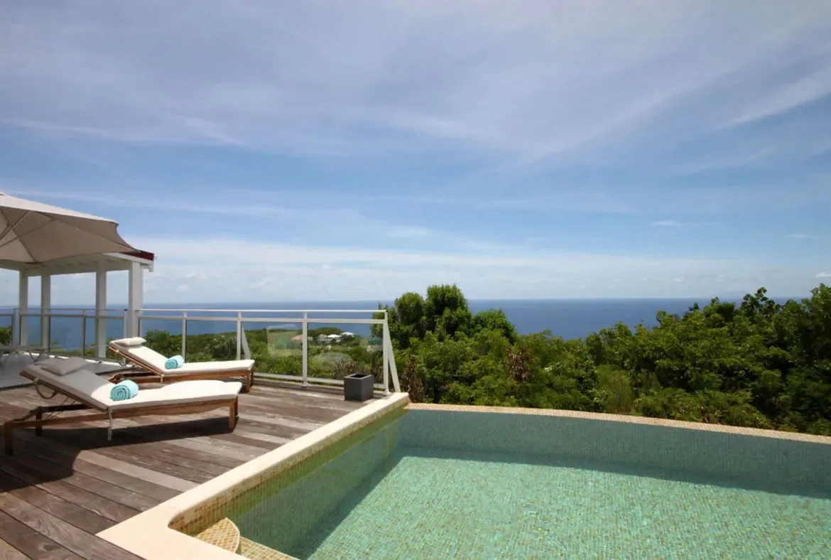 Relax by the shimmering pool where the turquoise water meets the infinite blue of the Caribbean horizon.