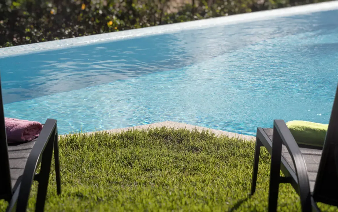 Relax by the edge of the sparkling infinity pool, where lush green lawns meet the shimmering turquoise waters of the Caribbean.