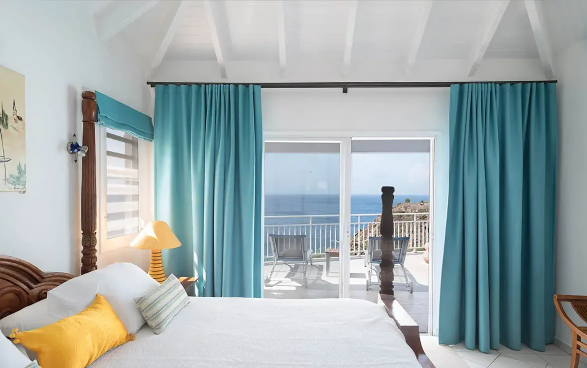 Wake to sweeping Caribbean views framed by turquoise curtains and a classic four-poster bed. Sliding glass doors open onto your private balcony with loungers—the ultimate indoor-outdoor retreat where the ocean is your first and last sight each day.