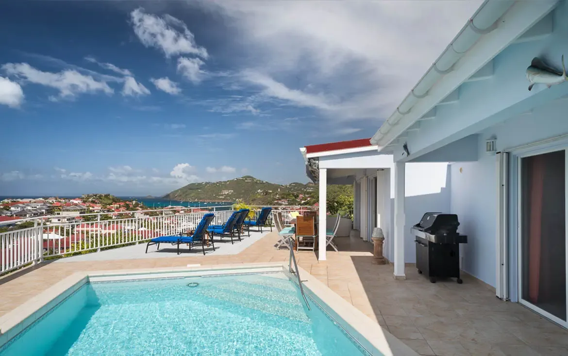 Perched high above Gustavia, a turquoise plunge pool anchors your private terrace. Four blue loungers invite sunbathing, while the covered veranda with BBQ awaits evening entertaining—all overlooking the Caribbean's most spectacular panorama.