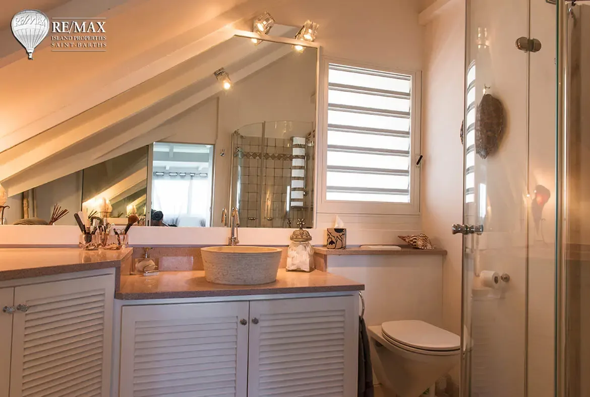 A bright bathroom with glass-enclosed shower and natural textures — freshen up in relaxed island style.