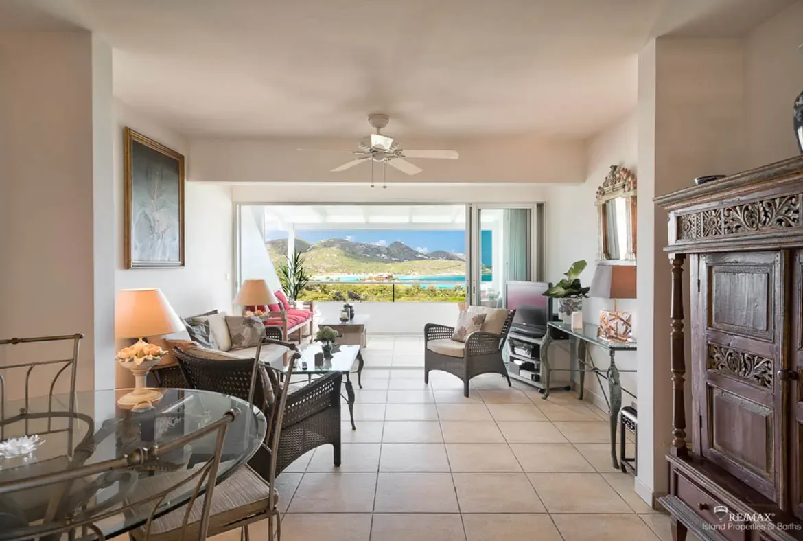 A bright living and dining area opens to the terrace — entertain with views of the turquoise bay beyond.