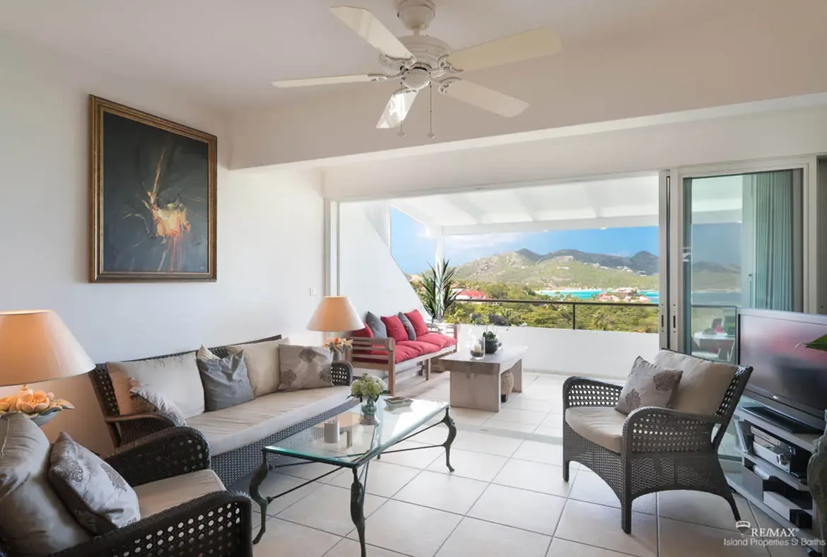 An open-concept living room flows seamlessly to the terrace — indoor-outdoor living with panoramic hill and ocean views.