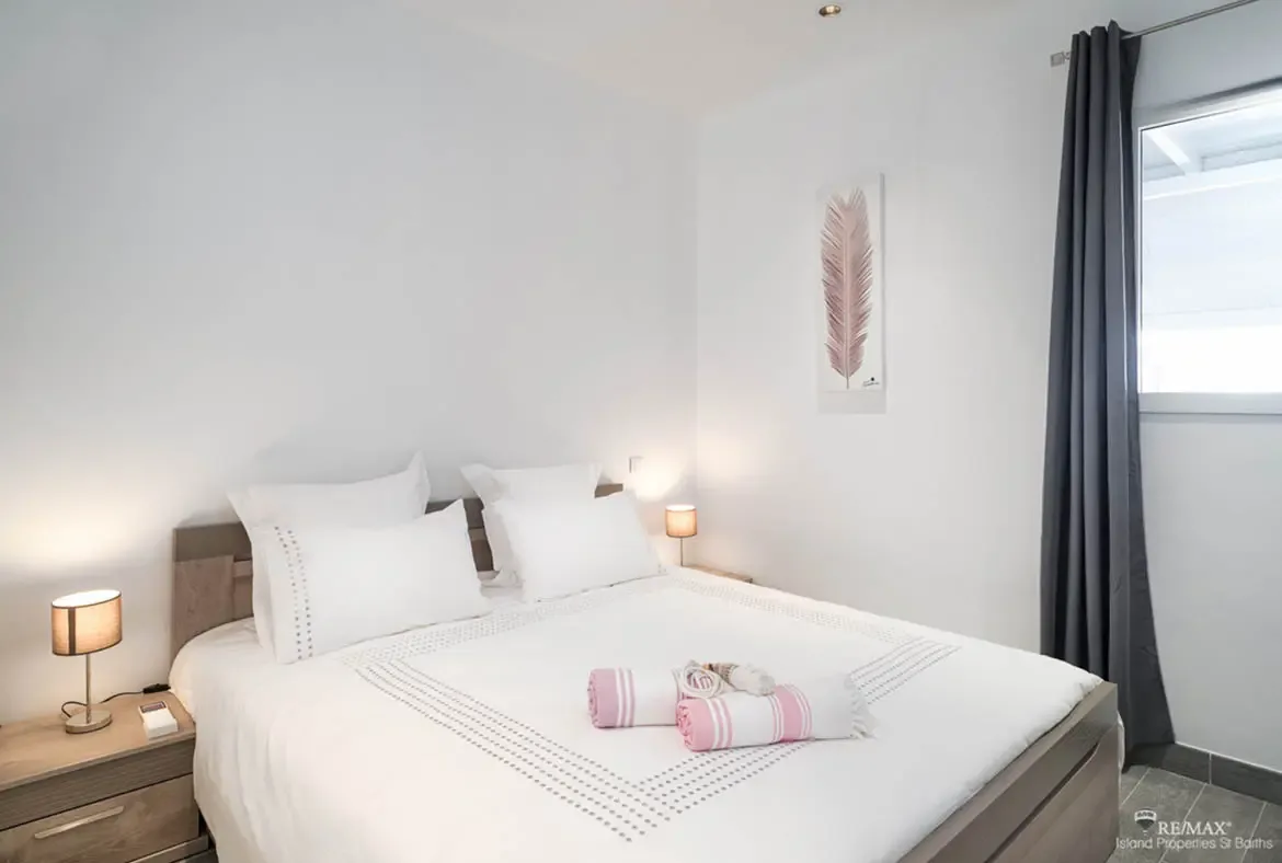 A bright, inviting bedroom with soft tones and crisp linens offers restful comfort in the heart of St. Barths.