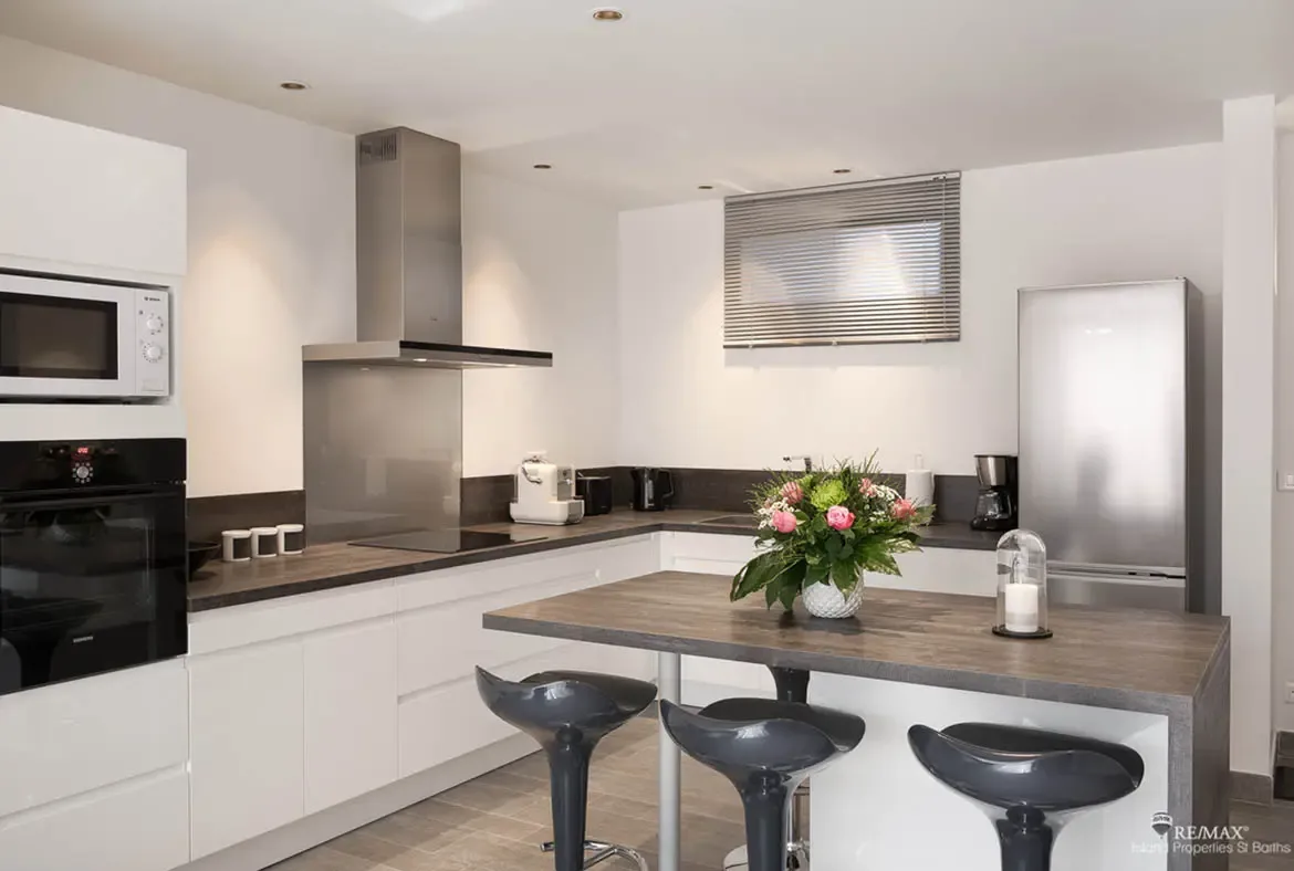 A sleek modern kitchen with island seating and premium appliances makes entertaining effortless in St. Barths.
