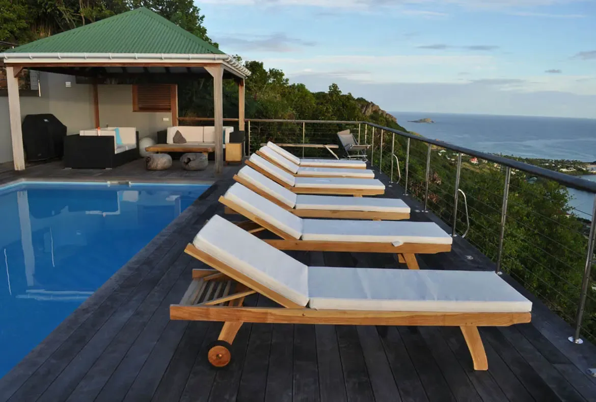Unwind on the private pool deck of Villa Agave Azul, where wooden lounge chairs frame panoramic ocean vistas and the gentle Caribbean breeze. Let the serene hillside setting and modern al fresco living space define your St. Barths retreat.                                                                                                                                                                                                                                                                  +
 