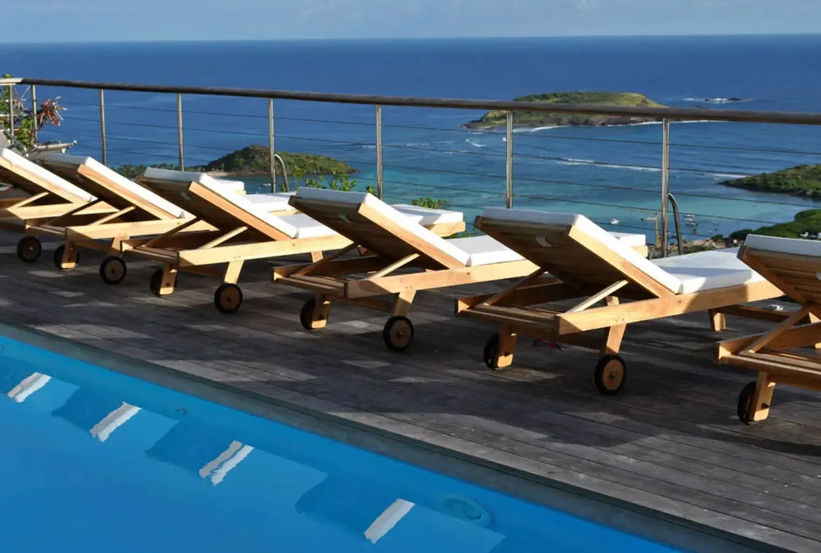 Sink into the tranquility of Villa Agave Azul's pool deck, where teak lounge chairs invite relaxation beneath the Caribbean sun. Breathe in the salt-kissed air as turquoise waters and distant islands frame an endless horizon, crafting moments of pure serenity.                                                                                                                                                                                                                                               +
 