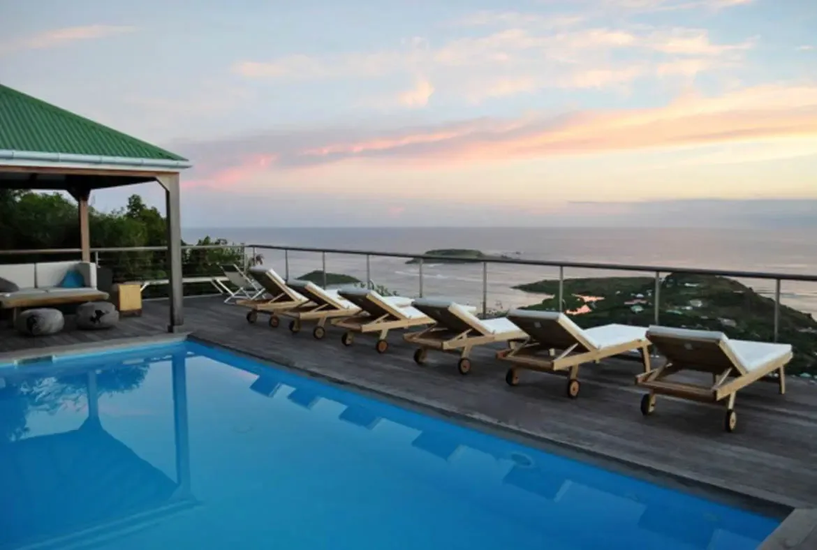 Unwind on the private pool deck of Villa Agave Azul as the Caribbean sunset bathes the horizon in golden-pink hues, with plush lounge chairs arranged for effortless relaxation beside the infinity-edge pool. Let the ocean breeze and panoramic island views of St. Barths set the rhythm for your escape.                                                                                                                                                                                                 +
 