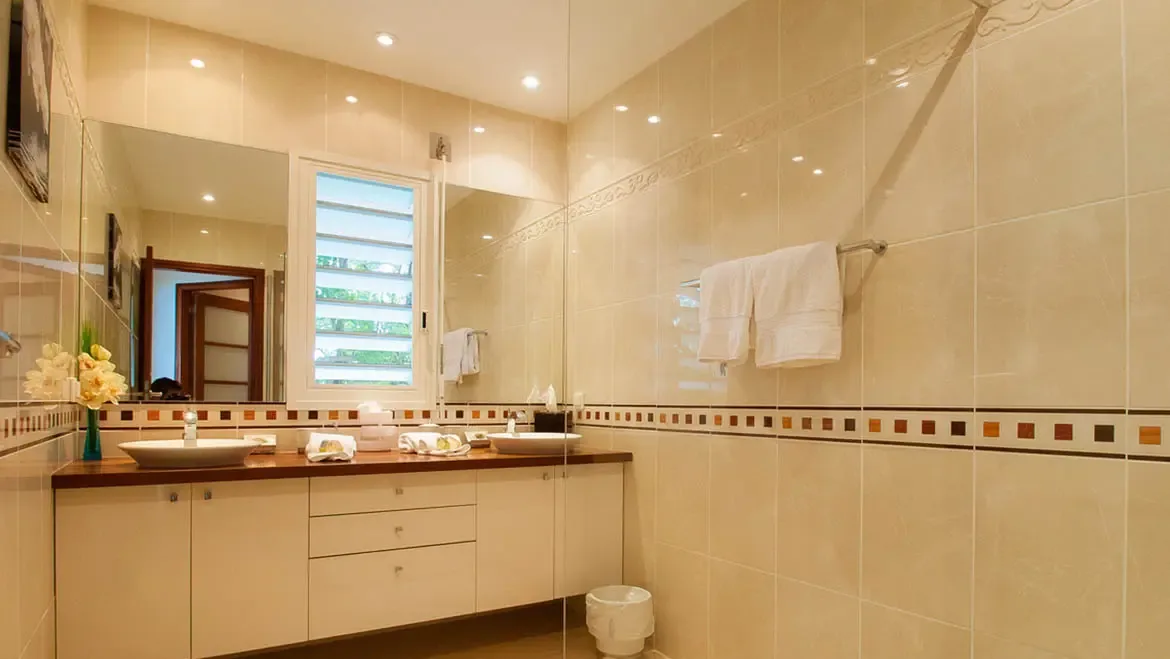 Unwind in this thoughtfully designed bathroom, where dual vessel sinks, warm neutral tones, and natural light from the louvered window blend luxury with tranquility. Every detail, from the polished wooden countertop to the plush towels, invites you to recharge before embracing St. Barths' island adventures.                                                                                                                                                                                          +
 