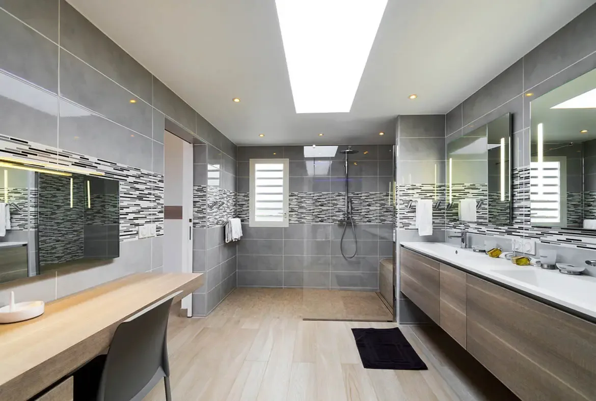 Step into this modern St. Barths sanctuary where a bright skylight illuminates the spacious bathroom's sleek gray tile and warm wood accents. Double vanities, a walk-in shower, and abundant natural light create a refined retreat for effortless luxury during your island escape.                                                                                                                                                                                                                           +
 