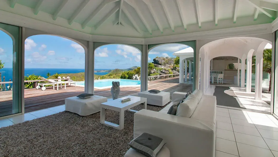 Unwind in Villa Byzance's spacious living area, where open archways frame panoramic Caribbean sea views and a glistening pool. Plush white sofas and breezy indoor-outdoor flow invite you to savor every moment of St. Barths' laid-back luxury.                                                                                                                                                                                                                                                       +
 