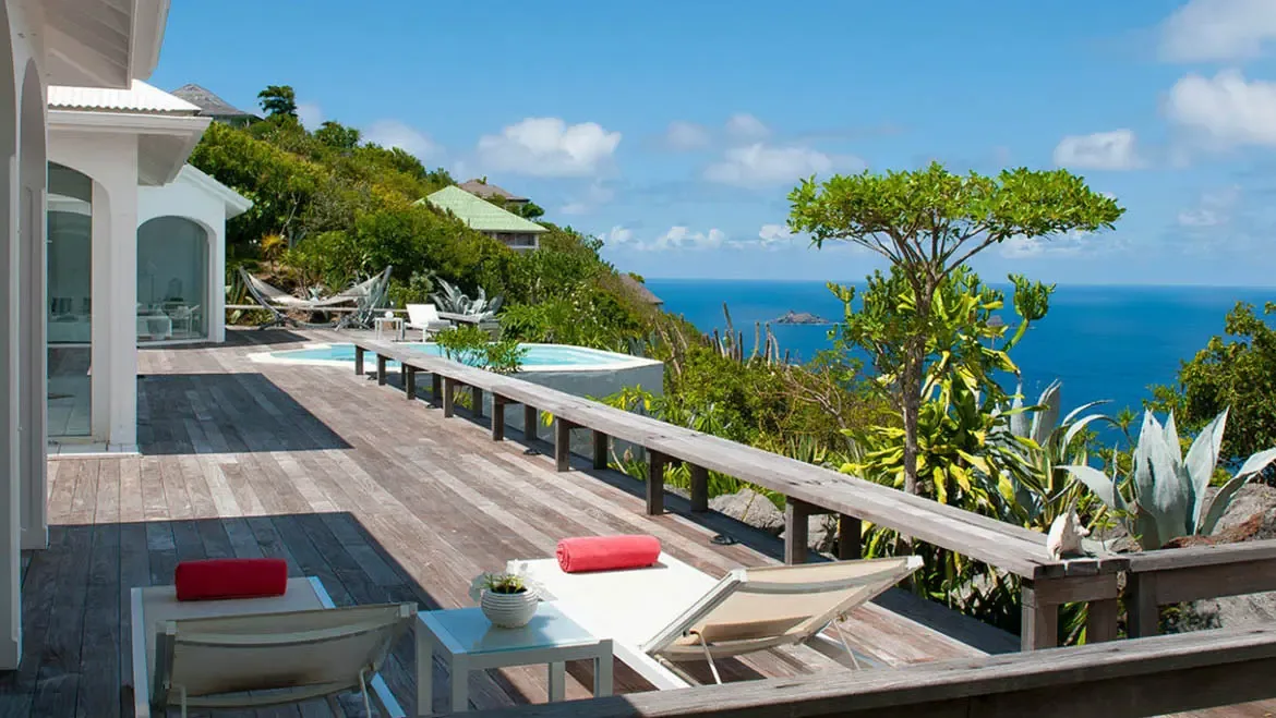 Indulge in the serene luxury of Villa Byzance's ocean-view terrace, where sun-drenched lounge chairs and an infinity pool blend seamlessly with the Caribbean's vibrant blue waters. Let the gentle breeze and panoramic coastal scenery transport you to a private paradise of relaxation and elegance.                                                                                                                                                                                                       +
 