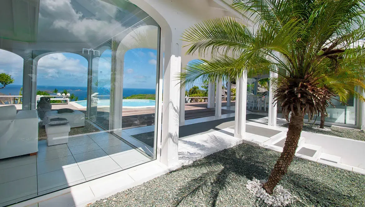 Step onto the sun-drenched terrace of Villa Byzance, where floor-to-ceiling glass doors dissolve boundaries between luxurious interiors and the endless Caribbean horizon. Breathe in the salt-kissed breeze as you unwind amid manicured gravel gardens and panoramic ocean vistas that stretch to the horizon.                                                                                                                                                                                                           +
 