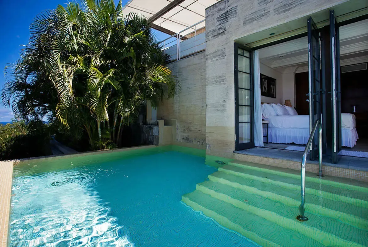 Step directly from plush linens into turquoise water—the ultimate swim-up luxury experience. Textured stone walls and tropical palms frame your private sanctuary, where the hardest decision is whether to nap or swim.