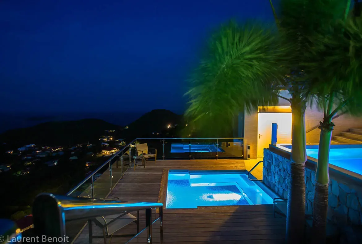 Watch the hillside town glow like fallen stars from Villa Donato's multi-level pool deck. The turquoise-lit plunge pool and warm interior lights create a private world above Colombier, where the blue hour melts into Caribbean night.