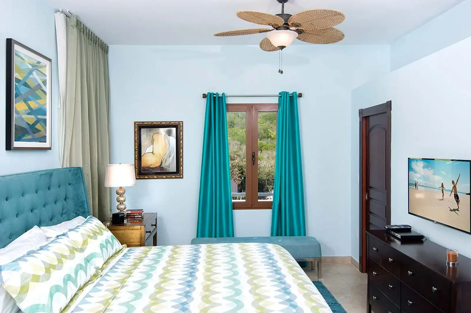 Neutral linens and warm wood tones create a tranquil secondary bedroom, where soft natural light filters through floor-to-ceiling drapes onto polished tile floors.