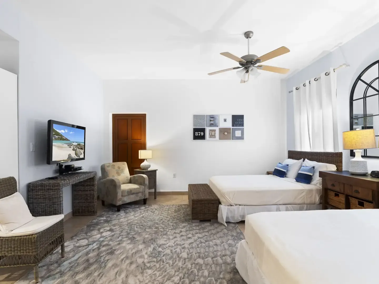 Elegant master bedroom with a white floral upholstered headboard, crisp white bedding, and a glimpse of the en-suite bathroom.