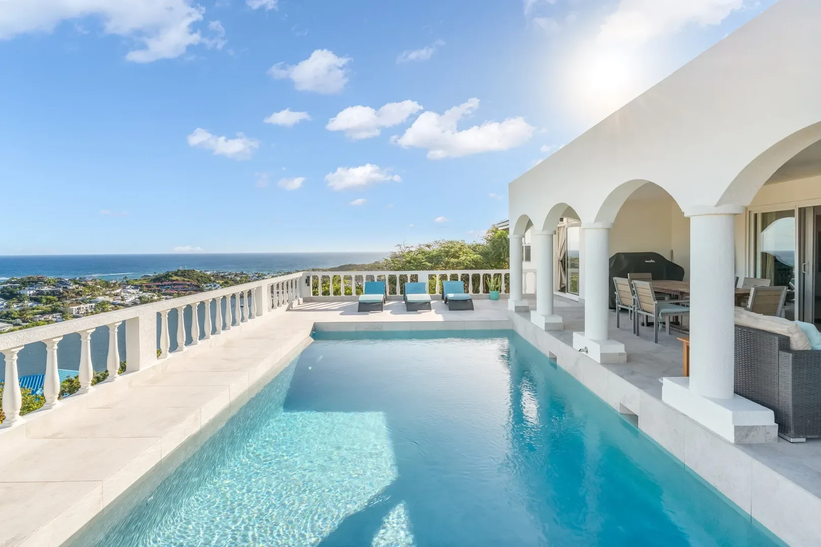 Luxury St. Maarten villa with infinity pool, ocean view, lounge chairs, and arched patio