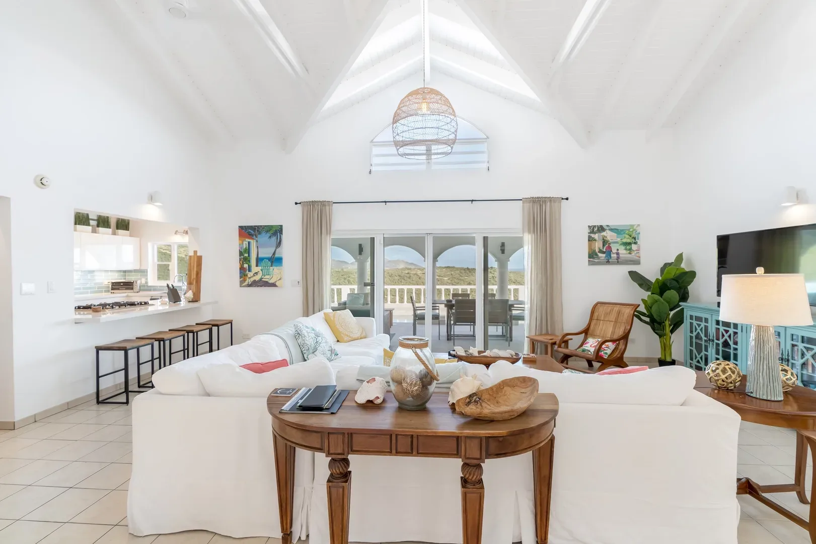 Bright open living area with white sectional sofa, wooden coffee table, and ocean view through glass doors in St. Maarten villa