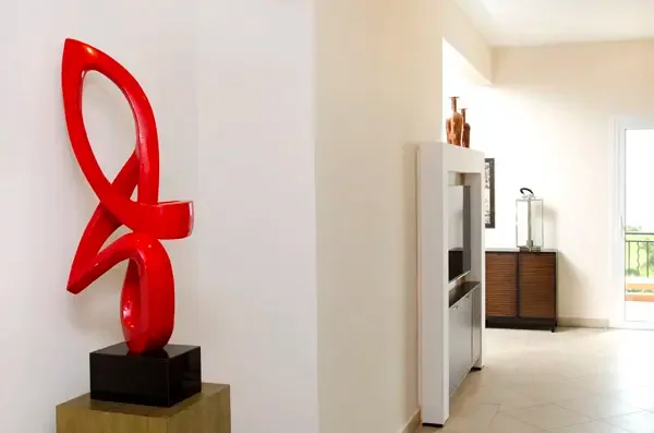 A striking red abstract sculpture adds a bold artistic touch to this thoughtfully curated space.