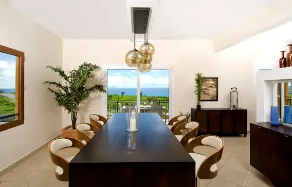 Gather around the elegant dining table with floor-to-ceiling doors framing the ocean — perfect for memorable dinner parties.