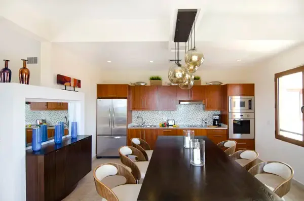Gourmet open kitchen with rich wood cabinetry and mosaic backsplash — a