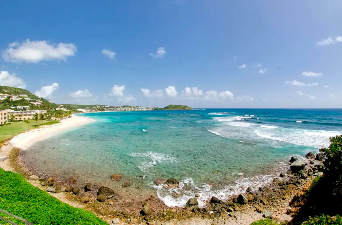 A stunning aerial view of Dawn Beach — turquoise waters, rocky shores, and swaying palms.