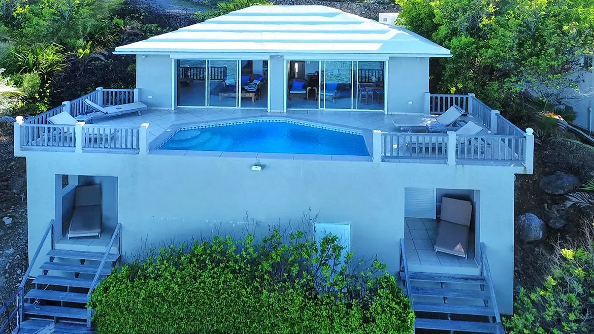 Modern two-story villa design with pool deck, surrounded by tropical vegetation.