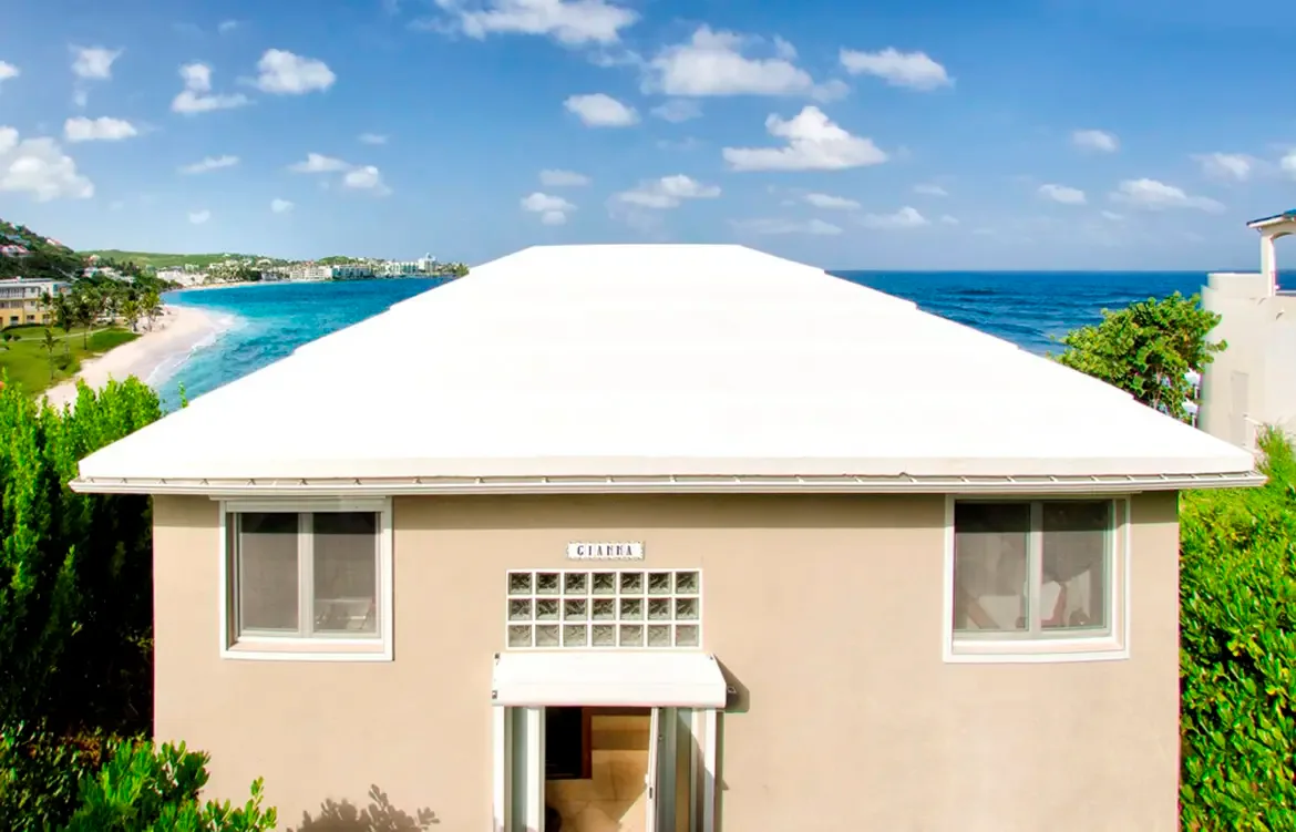 Charming beachfront living with sliding glass doors opening directly to sand and sea.