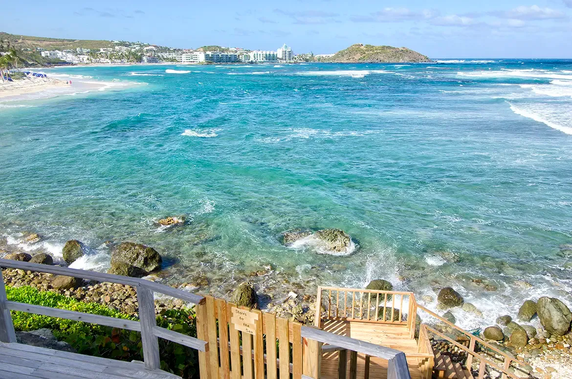 A scenic wooden walkway leads from your villa to the rocky shore and turquoise ocean.