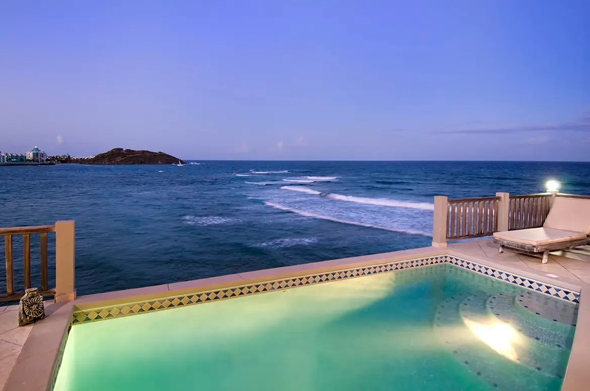 Evening ambiance with pool lights reflecting on the water and ocean views at dusk.