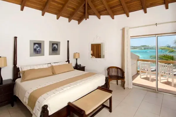 A four-poster bed framed by ocean views — sleep in style in your beachfront sanctuary.
