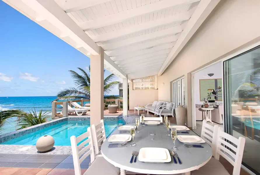 Dine al fresco in style — your covered outdoor dining area frames the pool and ocean like a living painting.
