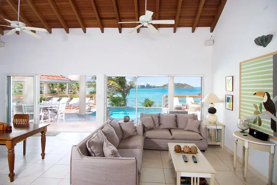 Relax in your spacious living area — L-shaped comfort with ocean views through glass doors.