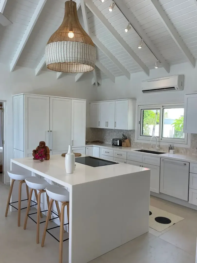 White modern kitchen with vaulted ceilings and natural light pouring through garden-view windows.                                                                                                                                                                                                                                                                                                                                                                                                                        +
 