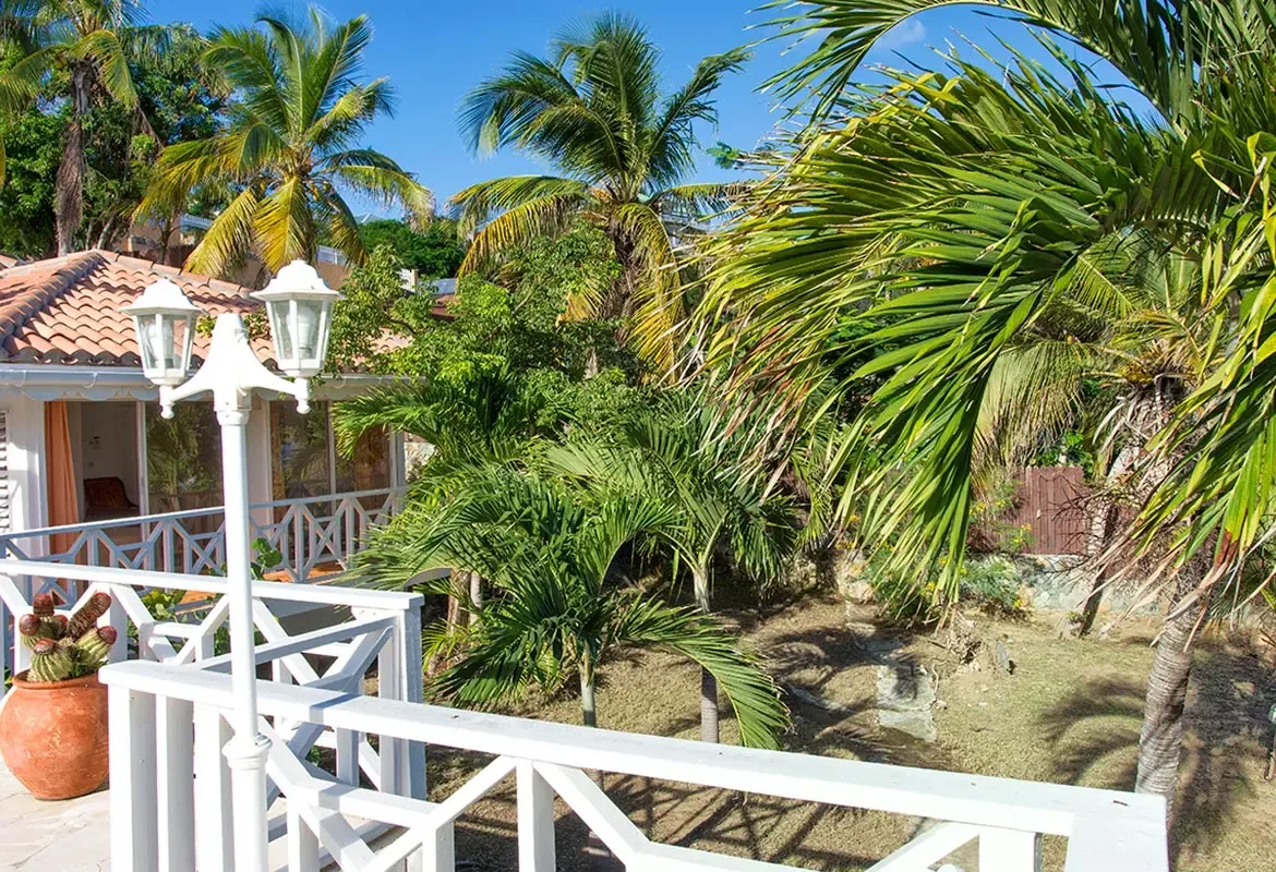 Balcony with white railing and double lamp post — palm trees frame your morning coffee with garden views.