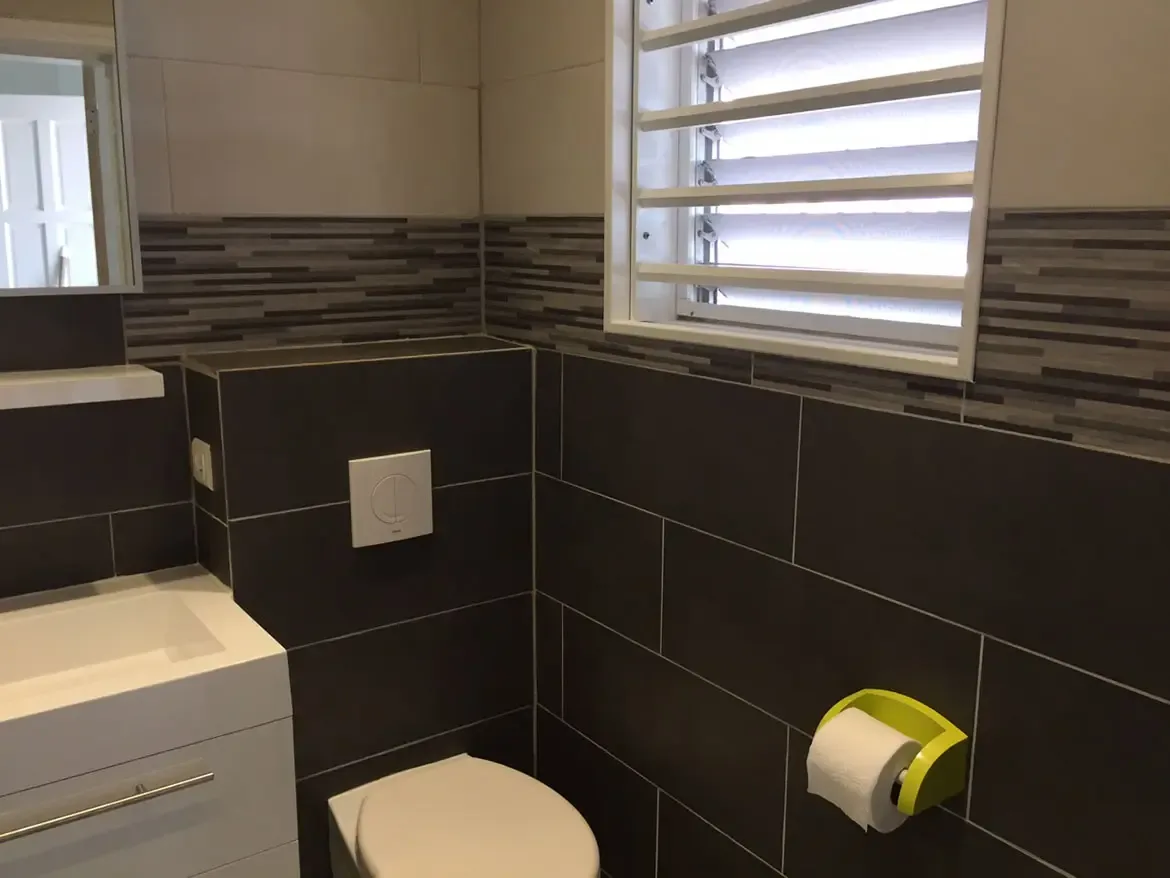 Modern toilet area with dark gray tiles — lime green accents brighten the compact space.