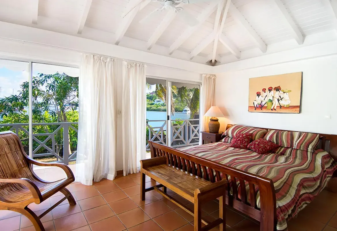 Master bedroom with vaulted ceiling and balcony access — sliding doors open to ocean views from your king bed.