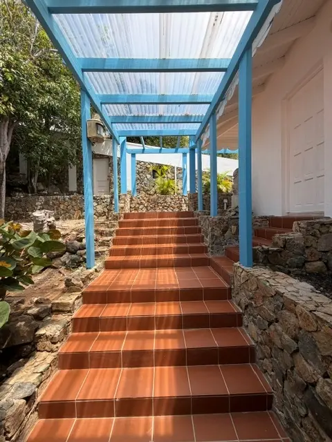 Terracotta steps beneath a blue covered walkway connecting Coralita guest rooms.